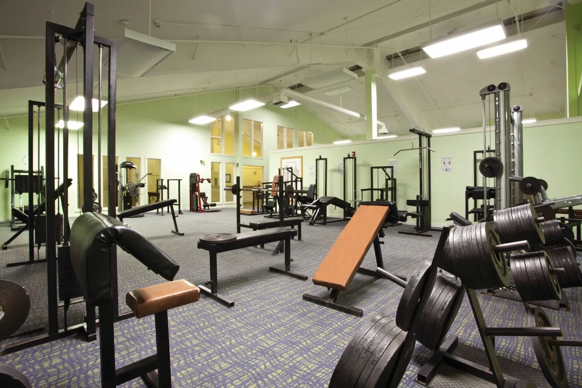 A dedicated weight training area featuring modern weightlifting equipment, benches, and exercise machines. Guests are seen participating in both solo and group fitness activities, fostering a sense of motivation and community.